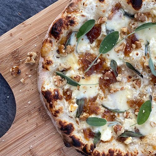 Pizza mit aufgeschlagenem Ziegenkäse, Feta, karamellisierten Zwiebeln, Salbei & Walnüssen